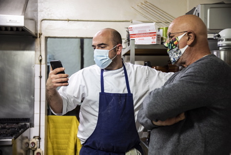 Guillaume Etchegorry et Christian Duplaissy du restaurant Ostalapia en renfort (photo) regardent les commandes de repas sur leur page Facebook. Hiriartia, le bar restaurant dans le bourg du village d'Ahetze au pays basque, à mis en place comme beaucoup de restaurateurs la vente à emporter pour sauver les meubles et sutout, garder le contact avec sa clientèle. Guillaume Etchegorry le patron et chef du restaurant est heureux de voir que les Aheztar et les habitants des villages alentours ou encore des ouvriers fidèles le soutiennent, lui et son équipe, en passant régulièrement commande chaque jour. Avec une moyenne de 15 à 20 repas par jour parfois jusquà 35, il garde le contact en ces jours sombres de distanciation.

Guillaume Etchegorry and Christian Duplaissy from the Ostalapia restaurant in reinforcement (photo) look at the meal orders on their Facebook page. Hiriartia, the bar restaurant in the village of Ahetze in the Basque country, has set up take-out sales like many restaurateurs to save furniture and above all, keep in touch with its customers. Guillaume Etchegorry the owner and chef of the restaurant is happy to see that the Aheztar and the inhabitants of the surrounding villages or even faithful workers support him and his team, by regularly placing orders every day. With an average of 15 to 20 meals a day, sometimes up to 35, he keeps in touch in these dark days of estrangement.

Ahetze, Pays Basque, Nouvelle Aquitaine, New Aquitaine, Basque Country, Pyrénées Atlantiques, Sud Ouest, France, Europe.