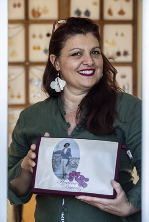 Hélène Demé Elzévir, de son nom de créatrice Hortense de Biarritz pose avec le portrait de sa grand mère (qui etait couturière) imprimé sur une pochette de sa fabrication. Hortense est à l'initiative de la création d'une technique spécifique de solidification des fleurs. Les bijoux de "Hortense de Biarritz" en fleurs solidifiées sont montés sur argent, des pièces uniques de bijoux solides qui tiennent des années. La pandémie du coronavirus étant passée par là, Hélène Demé Elzévir qui est également comédienne depuis 2016 avec à son actif, l'écriture spectacle PILE POIL qui l'a révélé et fait un tabac a perdus pas moins de 45 dates de spectacle. Un vrai cauchemar pour elle, mais une raison de plus de ne rien lâcher et de produire un peu plus de bijoux et d'objets en attendant le retour des beaux jours et celui de la scène. Soutenez là ! et "Offrez des fleurs qui ne fanent jamais !" c'est ici avec la possibilité de commande en ligne : www.hortensedebiarritz.com

Hélène Demé Elzévir, her designer name Hortense de Biarritz, poses with the portrait of her grandmother (who was a seamstress) printed on a pocket of her own making. Hortense initiated the creation of a specific technique for solidifying flowers. The jewelry of "Hortense de Biarritz" in solidified flowers are mounted on silver, unique pieces of solid jewelry that last for years. The coronavirus pandemic having been there, Hélène Demé Elzévir who has also been an actress since 2016 with to her credit, the writing show PILE POIL which revealed it and made a splash lost no less than 45 show dates. A real nightmare for her, but one more reason not to give up and to produce a little more jewelry and objects while waiting for the return of the beautiful days and that of the scene. Support there! and "Give flowers that never wither!" it is here with the possibility of ordering online: www.hortensedebiarritz.com

Arbonne, Pays basque, 64 , Nouvelle Aquitaine, Pyrénées Atlanti