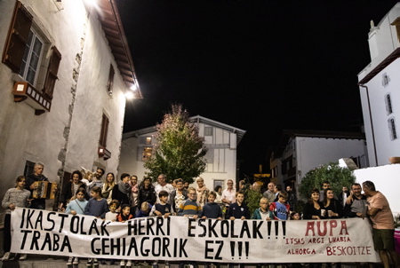 Banderole de revendication de l'Ikastola du village d'Ahetze pour faire valoir que l Ikastola à autant de droits que l'école publique du village lors de la soirée et fête populaire basque, sur la place historique du village d'Ahetze à l'initiative de l'Ikastola ALHORGA (Ecole en langue basque) et en collaboration avec le comité des fêtes du village (Ahetzeko Mozkor Banda,) dans le cadre des fêtes de ce petit village de la province du labourd.
Banner of claim of the Ikastola of the village of Ahetze to stop the "Sticks in the wheels and complication of the current majority" during the evening and popular Basque festival, on the historic square of the village of Ahetze on the initiative of the Ikastola ALHORGA (School in the Basque language) and in collaboration with the committee of the village festivals within the framework of the festivals of this small village of the province of labourd.
Ahetze, Pays Basque, Region Nouvelle-Aquitaine, Pyrenees-Atlantiques France, Europe.
Basque Country, New Aquitaine Region