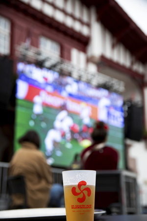 Coupe du monde de rugby 2023, un verre de biere en plastic réutilisable avec une croix basque avec projection et écran géant à Bidart sur la côte basque, place Sauveur Atchoarena sur le parvis de la mairie pour assister aux quatre matches des quarts de finale. Ici match Angleterre et Fidji du 15 octobre à 17h00. Un événement organisé par la Mairie de Bidart en partenariat avec le bar-restaurant Elissaldia, le Bar du Fronton et l'Auberge Koskenia.
Rugby World Cup 2023, a reusable plastic beer glass with a Basque cross with projection and giant screen in Bidart on the Basque coast, Place Sauveur Atchoarena on the town hall square to watch the four quarter-final matches. Here England and Fiji match on October 15 at 5:00 p.m. An event organized by Bidart Town Hall in partnership with the Elissaldia bar-restaurant, the Bar du Fronton and the Auberge Koskenia.
Bidart, Pays Basque, Euskal Herri, Basque Country, Nouvelle Aquitaine, New Aquitaine, Pyrénées Atlantiques, Sud Ouest, France, Europe.